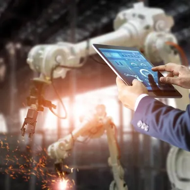 A person holding a tablet in front of an industrial machine.