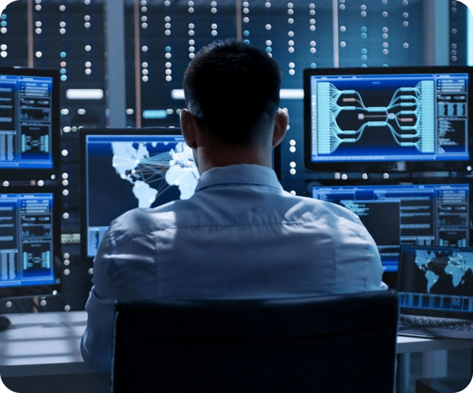 A man sitting in front of multiple computer screens.